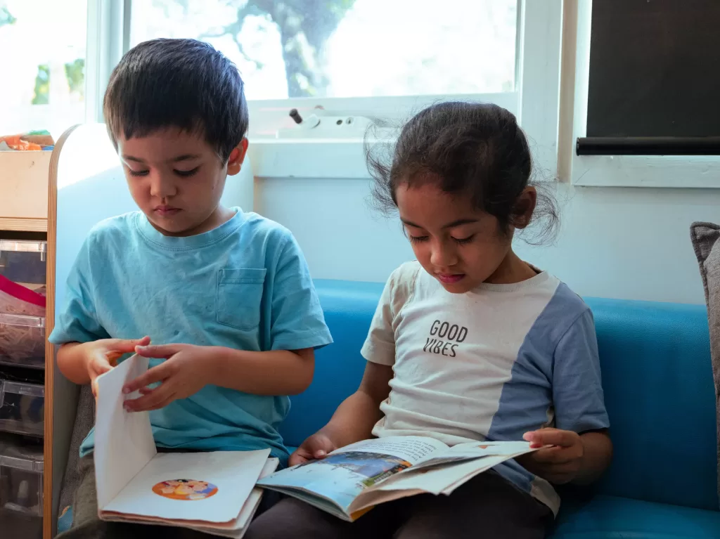 Kinderworld Early Learning Centre children sitting on couch reading picture books during quiet literacy time