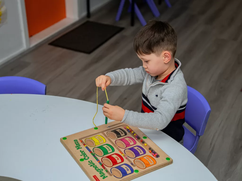 Kinderworld Early Learning Centre child engaged in fine motor activity with magnetic colour maze at table